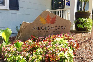 Arbors at Cary Apartment homes stone sign and flowers