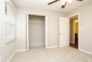 Interior Unit Bedroom, new carpeting, ceiling fan, windows, neutral toned walls.