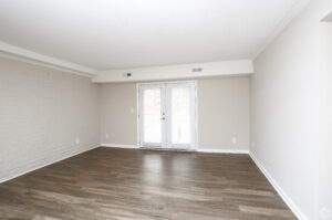Interior Living Room, wood floors, neutral toned walls, balcony doors, brick wall.
